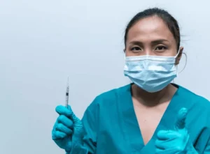 Gambar seorang perawat profesional yang sedang memegang alat suntik dengan sikap percaya diri dan ramah