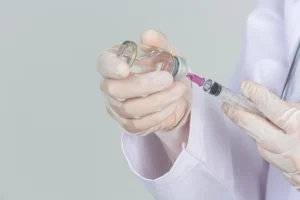 Gambar seorang perawat sedang memegang botol vitamin dan alat suntik dengan posisi yang rapi dan profesional